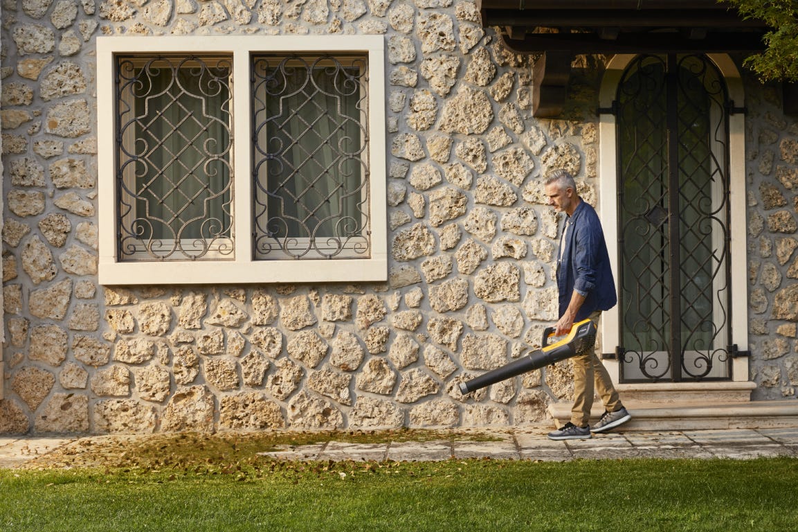 Man cleaning pathway from leaves using a STIGA SAB 500 AE battery-powered leaf blower.