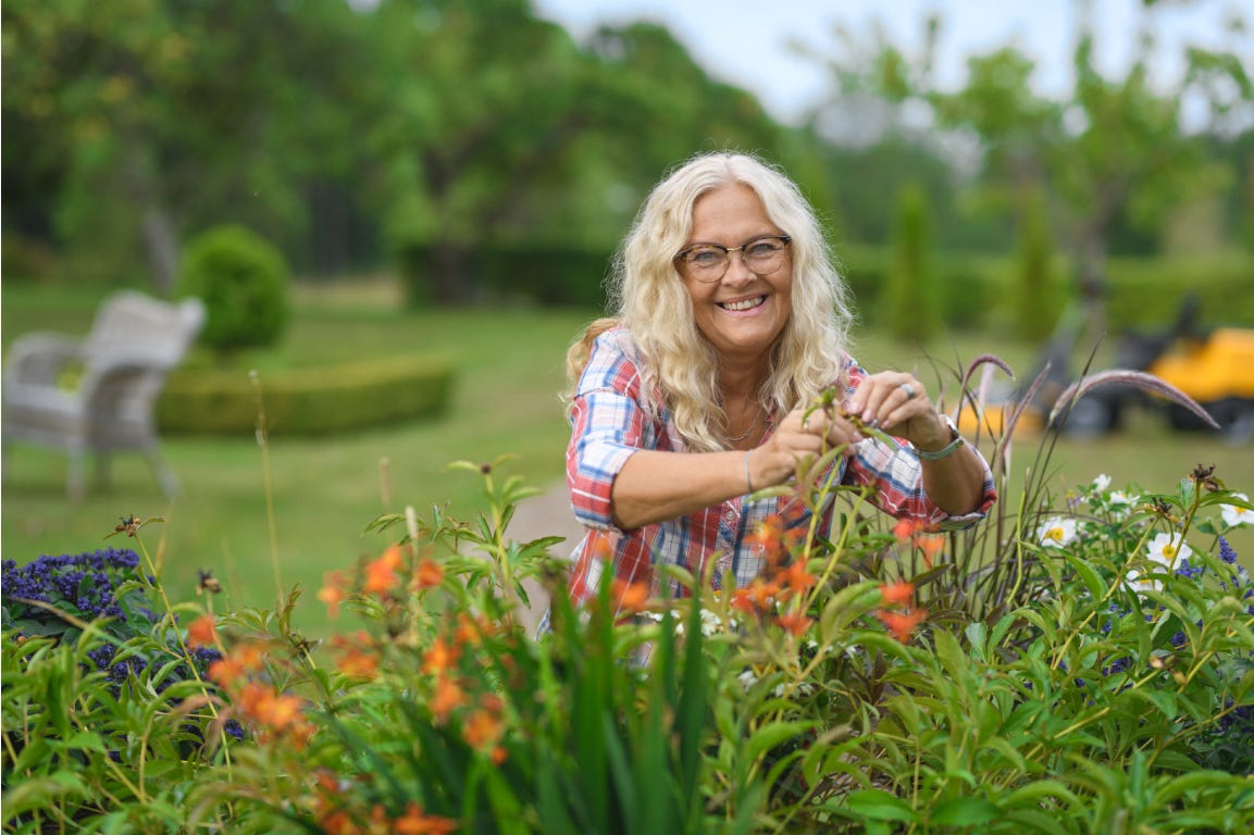 Smiling, happy womani taking care of red flowers 