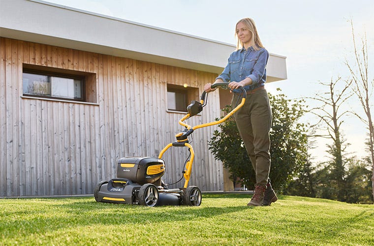 Man with a STIGA Multiclip mulching yellow lawn mower cutting grass