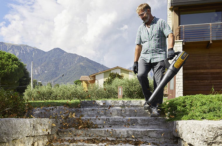 Man using STIGA battery blower to remove leaves from stairs