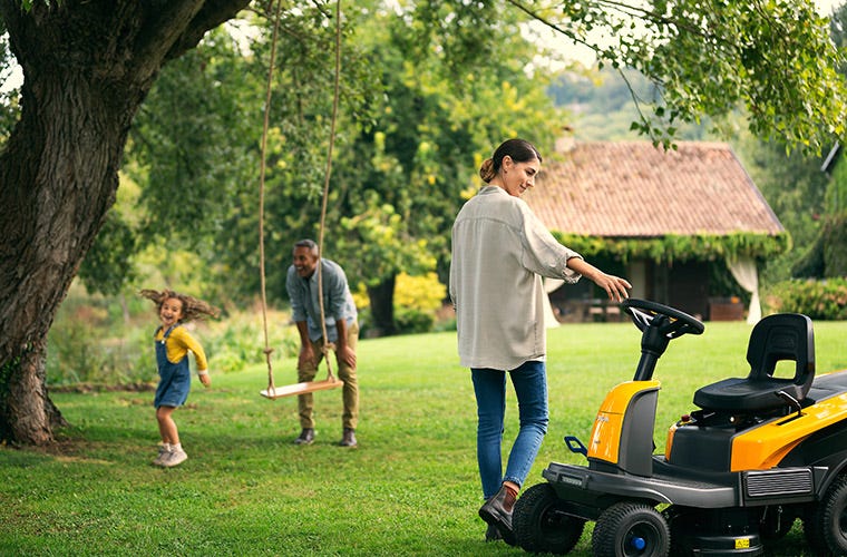 Die Familie genießt die Zeit im Garten, im Vordergrund der Aufsitzmäher von STIGA