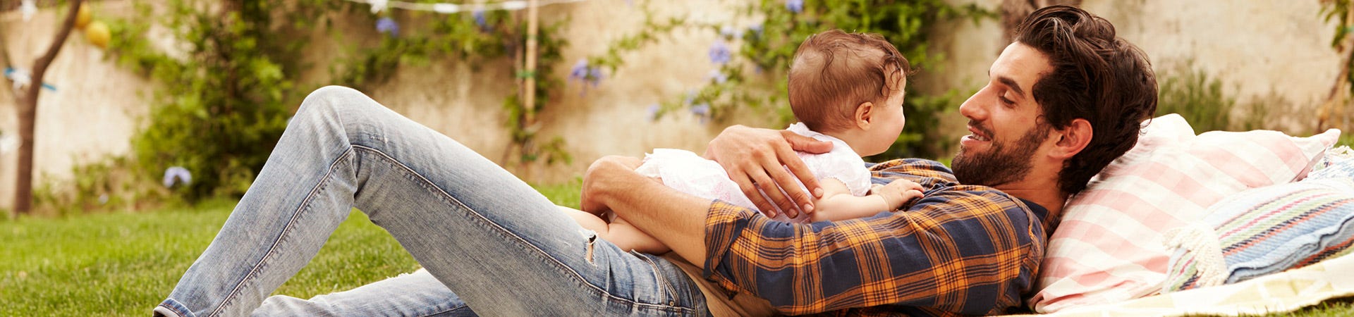 A father with his baby born laying and smiling on the garden
