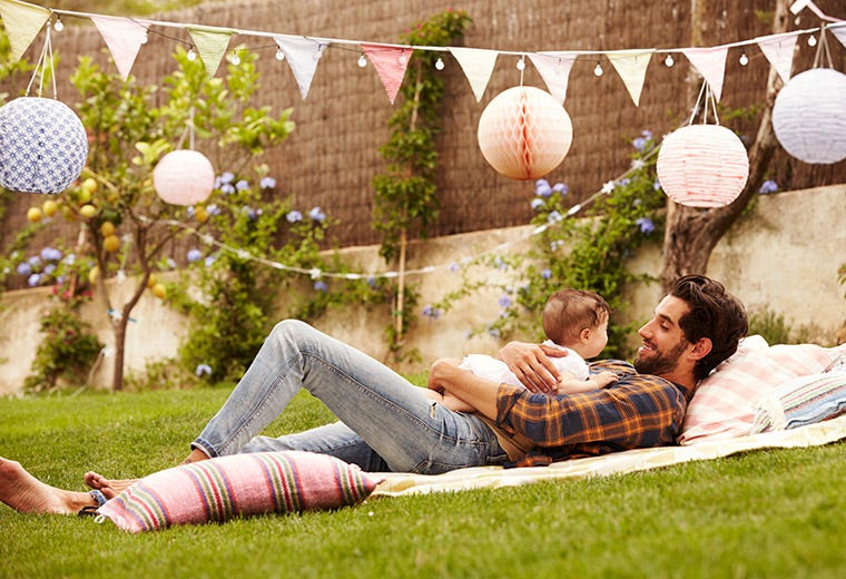 A father with his baby born laying and smiling on the garden