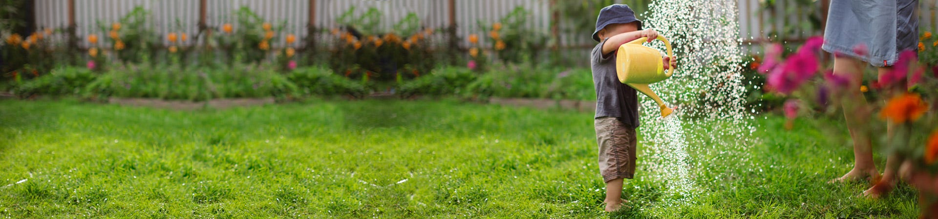 A child that plays in the garden with a watering can