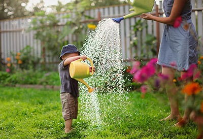 A child that plays in the garden with a watering can